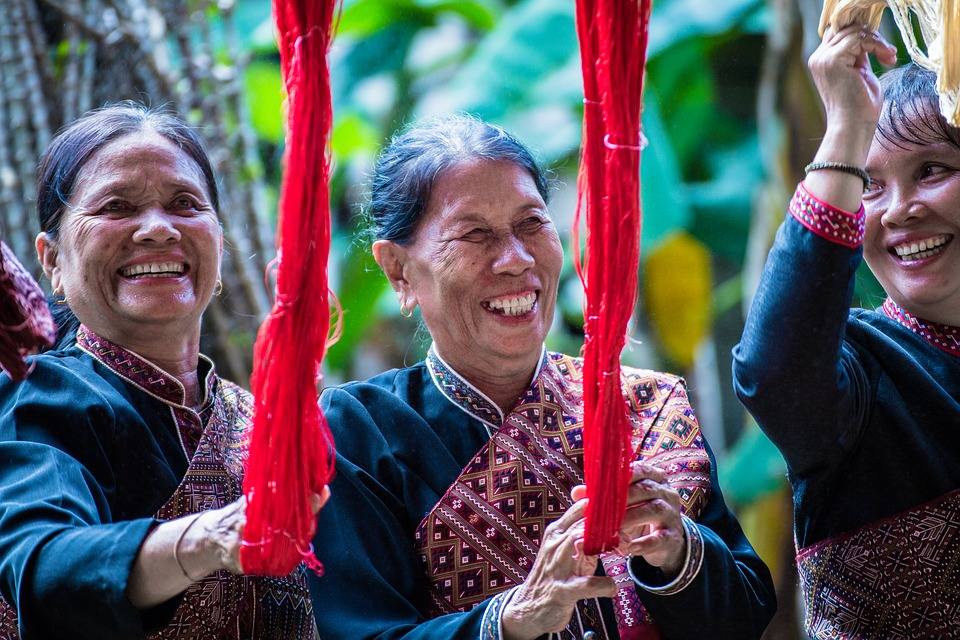 trzy uśmiechnięte kobiety trzymające czerwone włókna jedwabiu